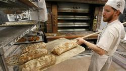 An employee at employee-owned King Arthur Flour Co. in Norwich, Vermont, takes bread from the oven. Photo Credit: AP Photo/Toby Talbot