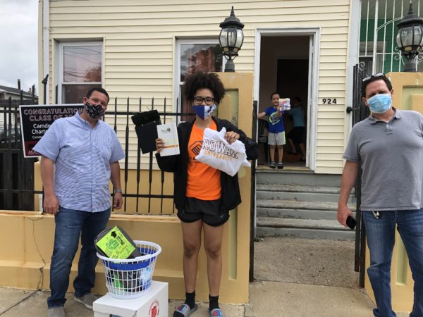 Brothers Brett Levin (left) and Andy Levin (right) of MHS Lift follow social distancing precautions while delivering a Rowan University sweatshirt and other fun items to MHS Lift Scholarship Fund recipient Jessica Rodriguez, 17, of Camden. Rodriguez plans to study economics at Rowan University.