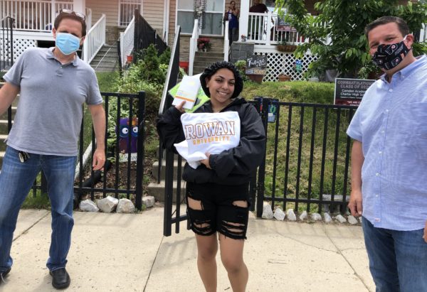 Brothers Andy Levin (left) and Brett Levin (right) of MHS Lift wear masks while delivering a Rowan University sweatshirt and other fun items to MHS Lift Scholarship Fund recipient Julianna Hilton, 18, of Camden City. Hilton plans to study biological sciences and psychology at Rowan University.